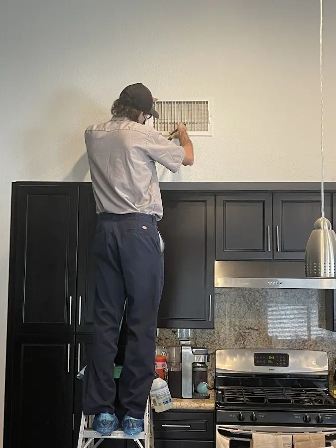 Technician inspecting an air vent during HVAC service in Canton
